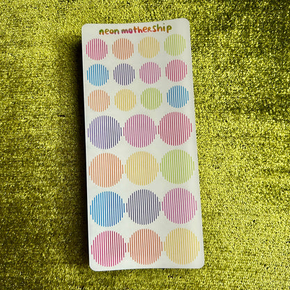 Pack of colorful dot stickers on a green textured background