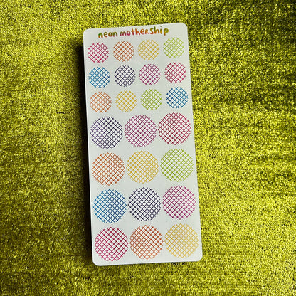 Sheet of colorful round stickers on a green textured surface