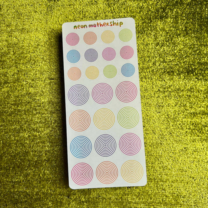 Pack of colorful circular stickers on a green textured surface