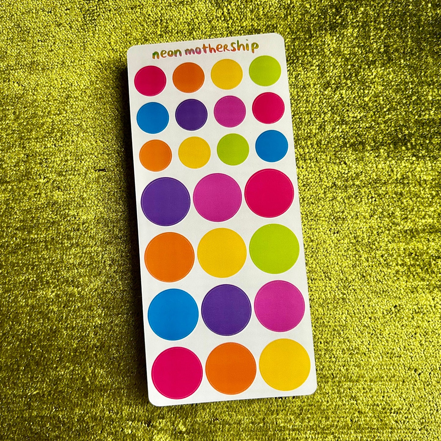 Colorful dot stickers on a green textured background