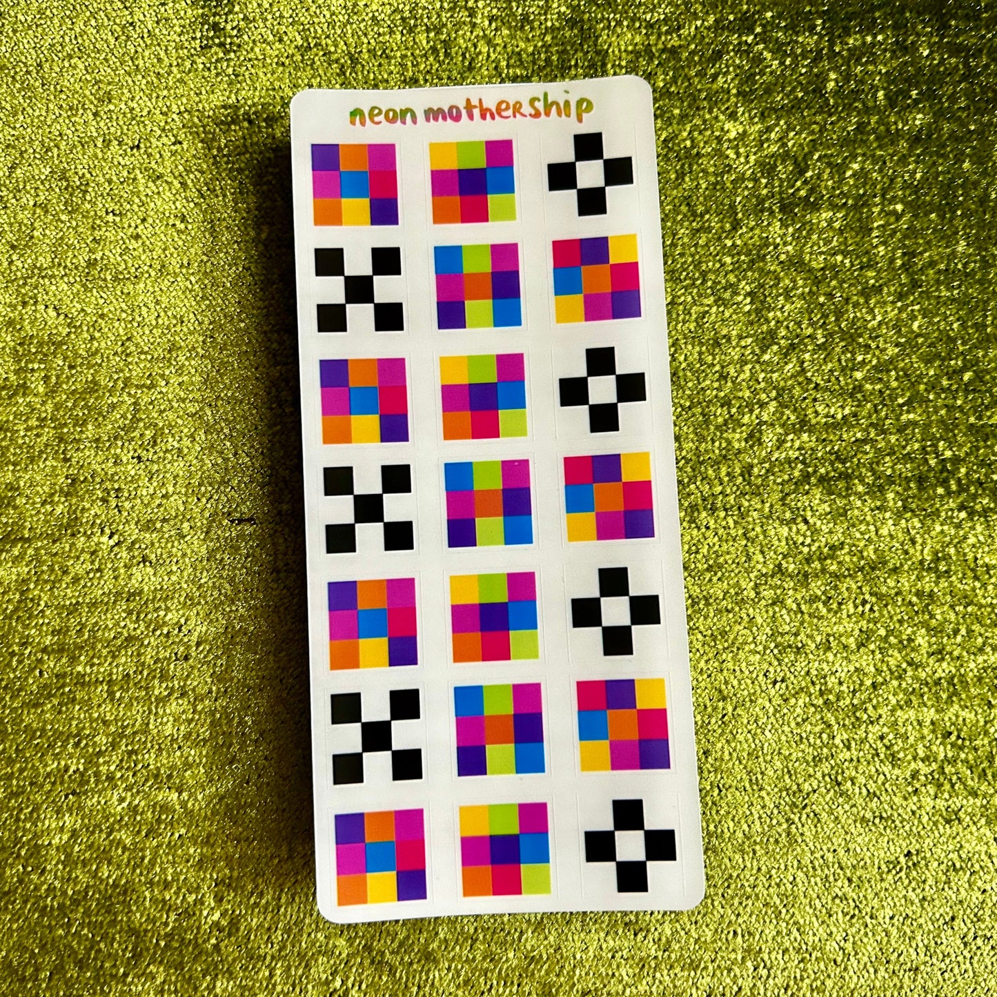 Sticker with colorful geometric patterns on a green textured surface