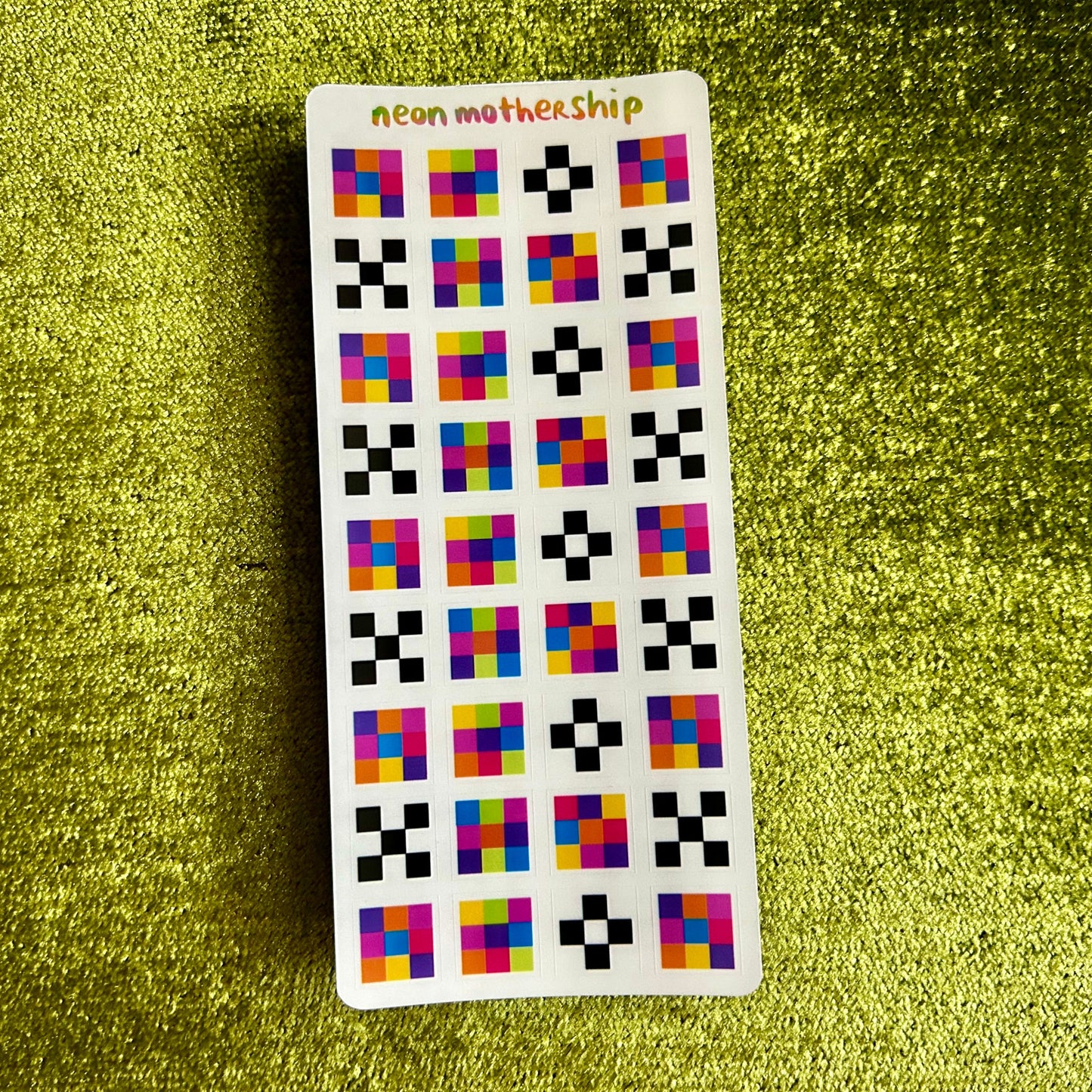 Sticker sheet with colorful geometric square stickers on a green textured background