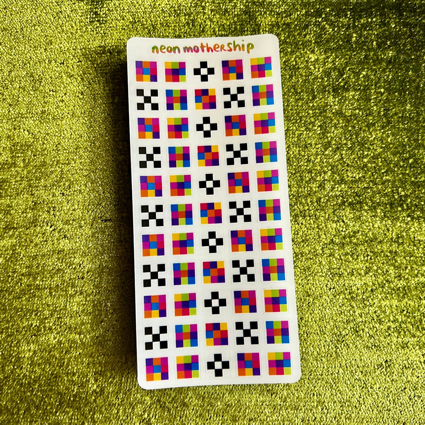 Card with colorful square pattern on a green textured surface