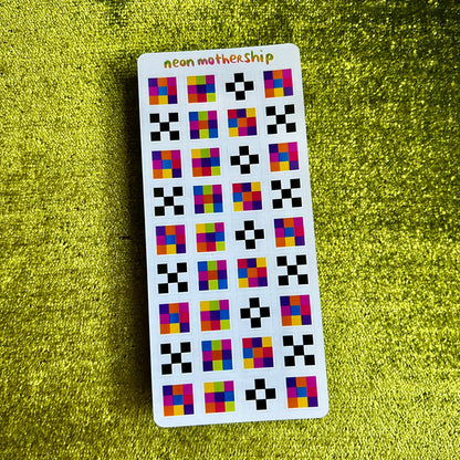 Sticker sheet with colorful square pattern stickers on a green textured surface