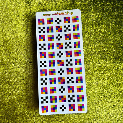 Sticker sheet with colorful square pattern on a green textured surface