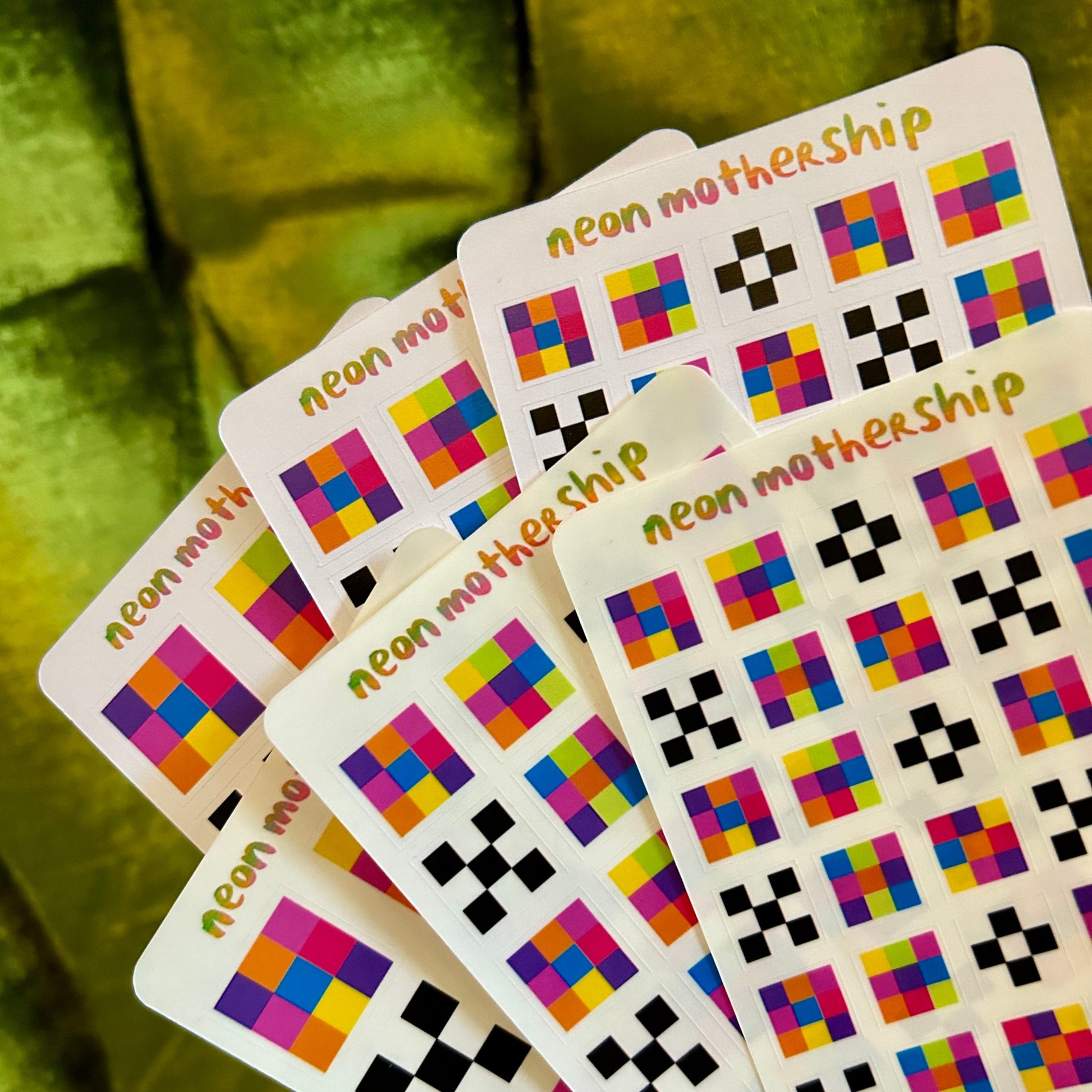 Colorful sticker sheets with geometric patterns on a green fabric background
