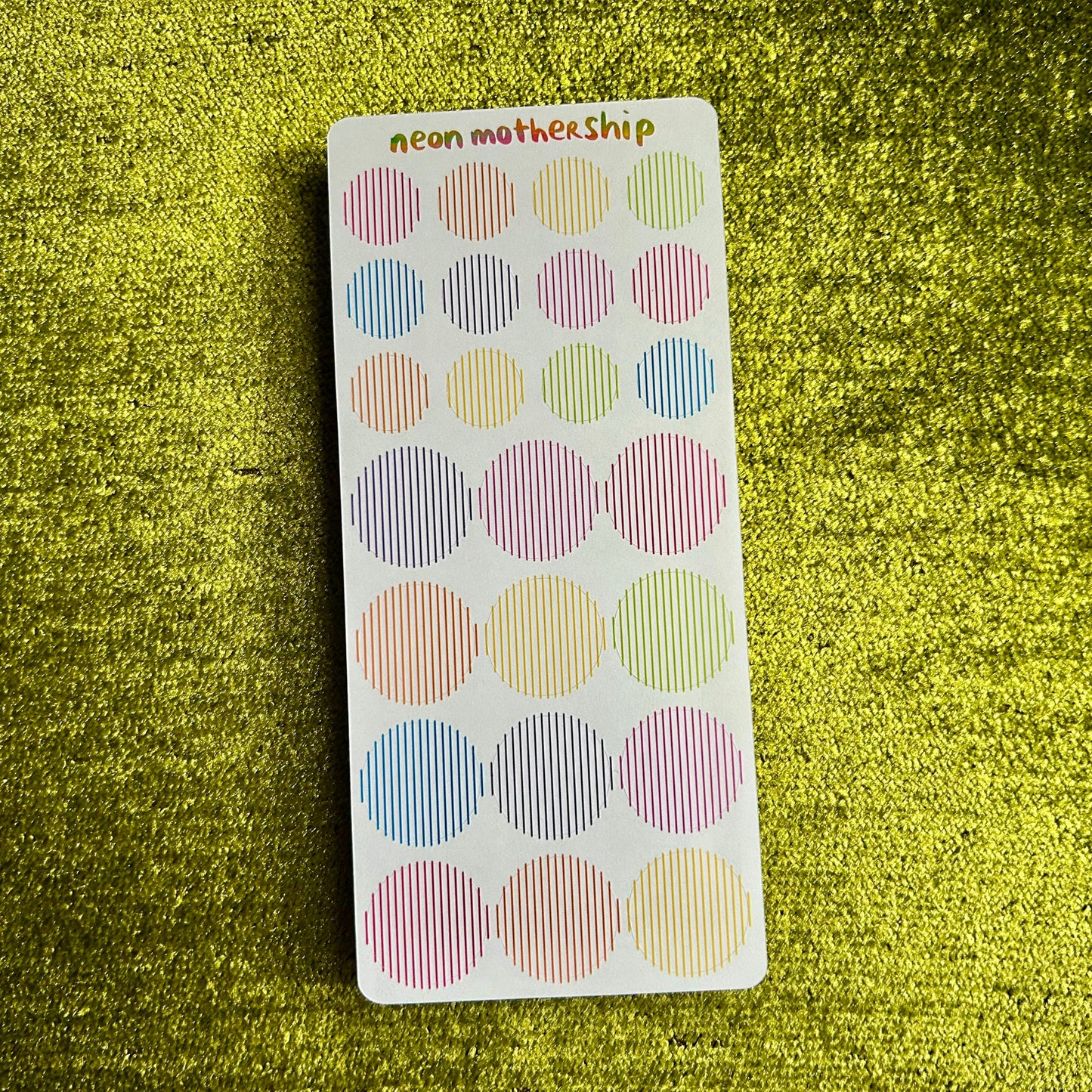 Pack of colorful round stickers on a green textured background