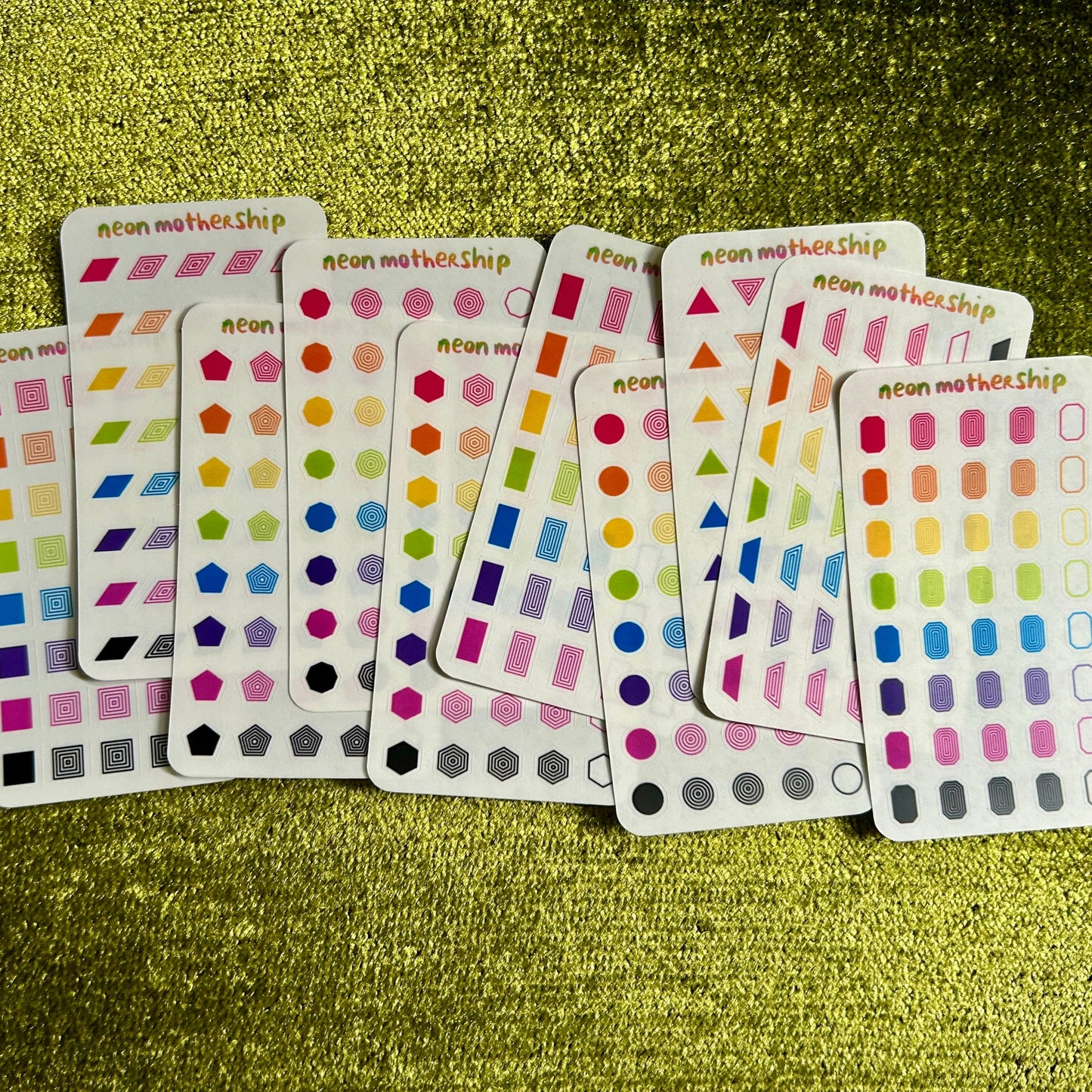 Set of colorful sticker sheets on a green textured surface
