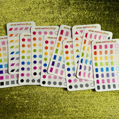 Set of colorful sticker sheets on a green textured surface