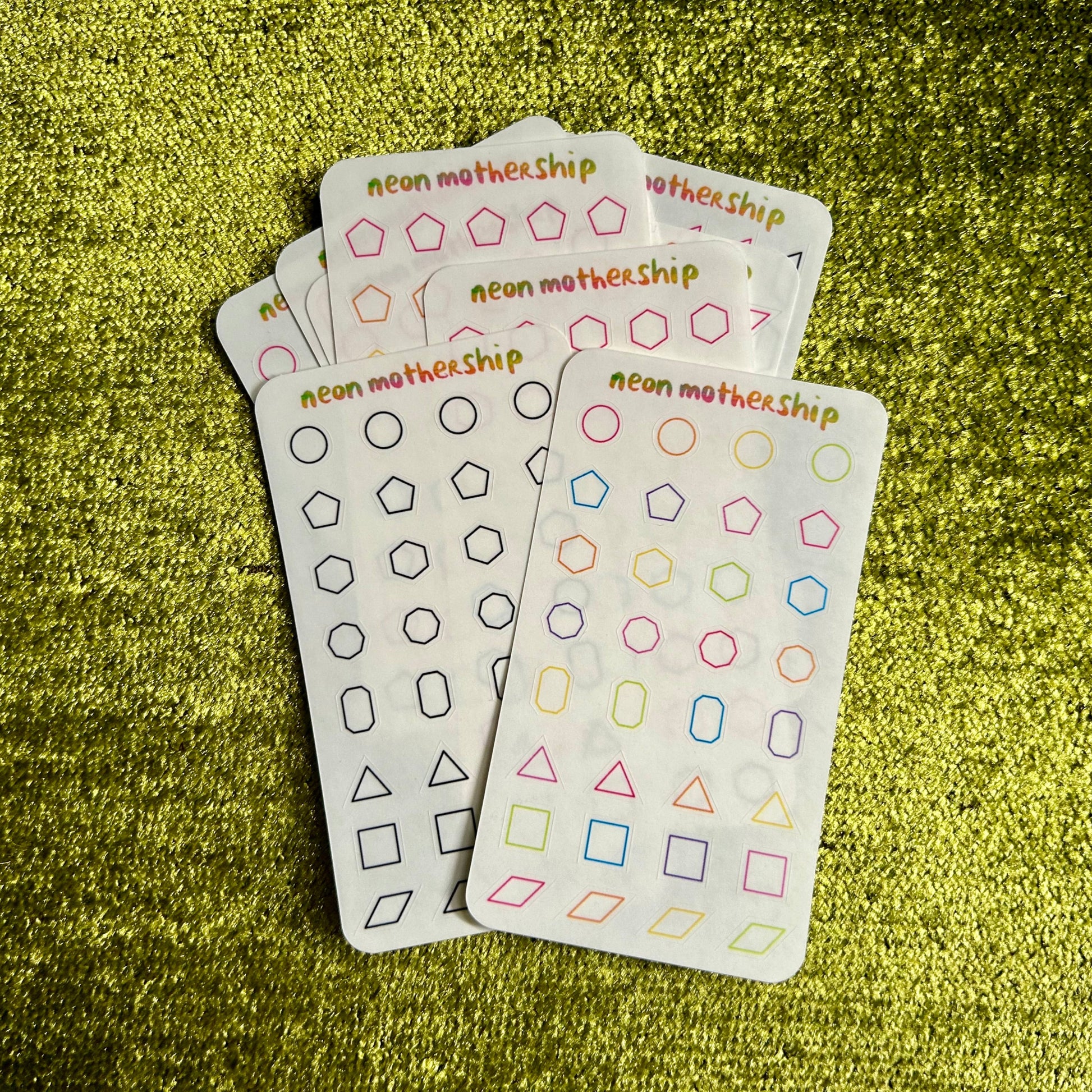 assorted sticker sheets with geometric pattern designs on a green textured surface
