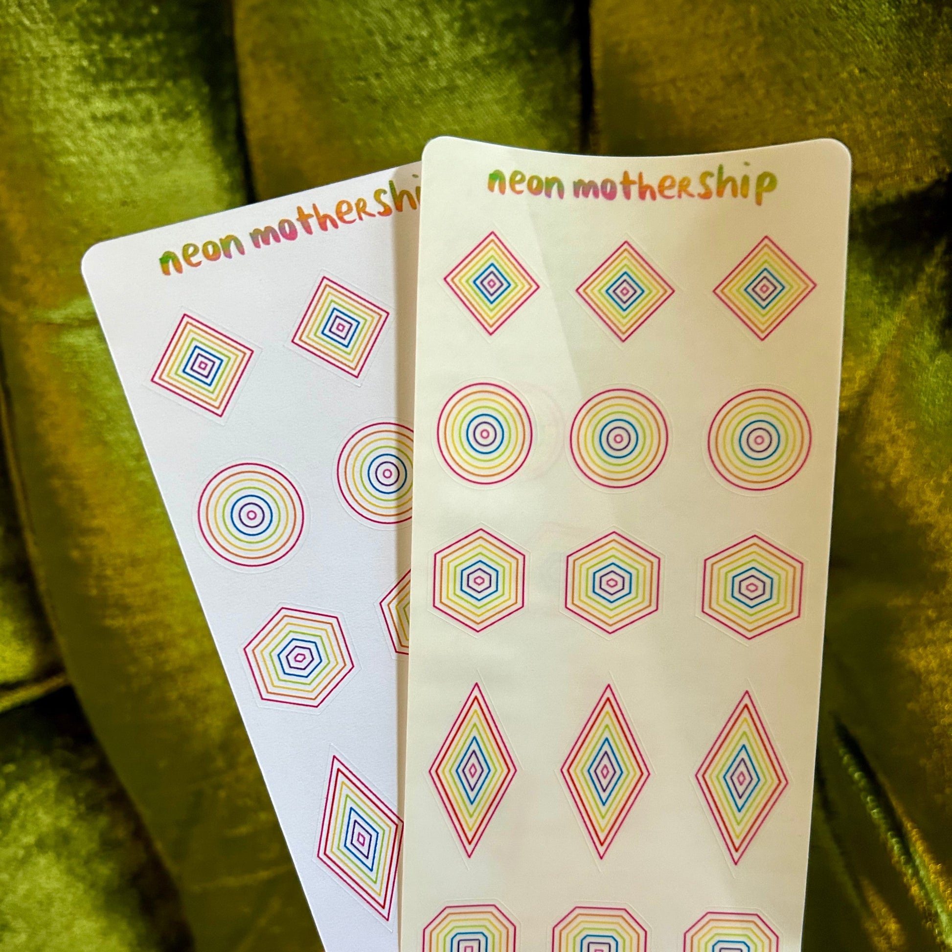 Two cards with geometric pattern designs held against a green fabric background