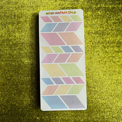 Sheet of colorful geometric stickers on a green textured surface