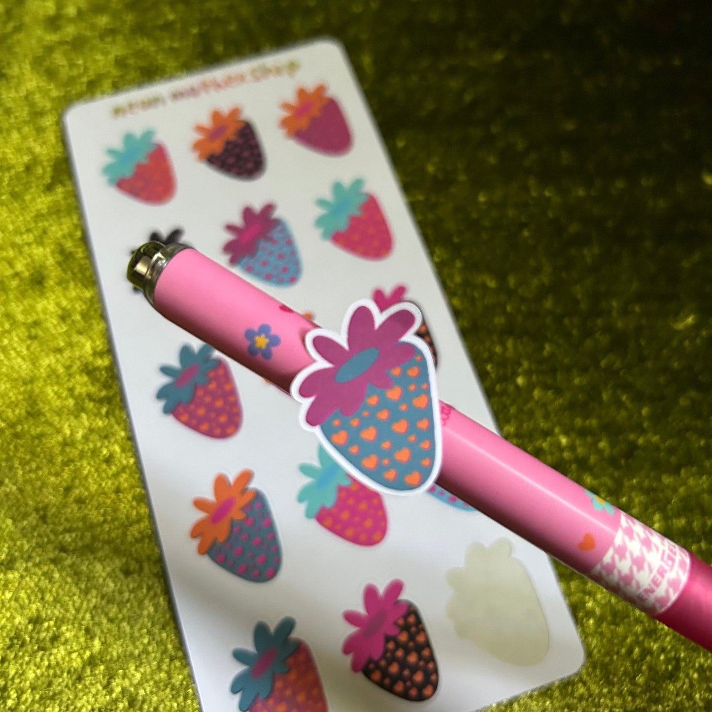 Pink pen with decorative spaceberry on a green textured background
