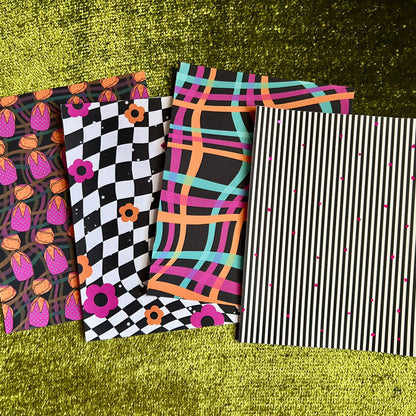 Four colorful sticker sheets with different patterns on a green textured surface