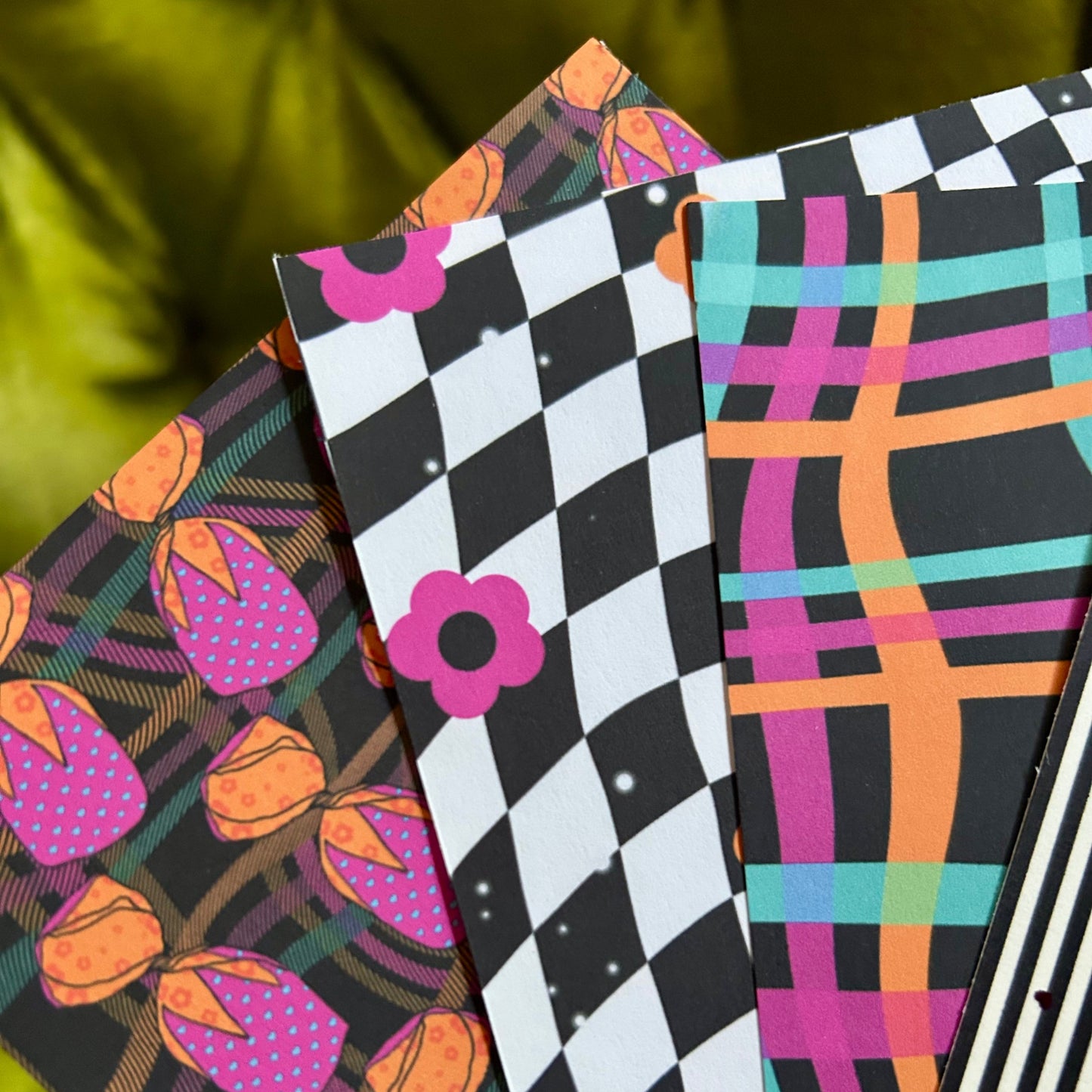Four colorful patterned sticker sheets stacked on a green surface