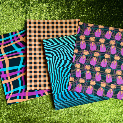 Four patterned sticker sheets on a green grass background