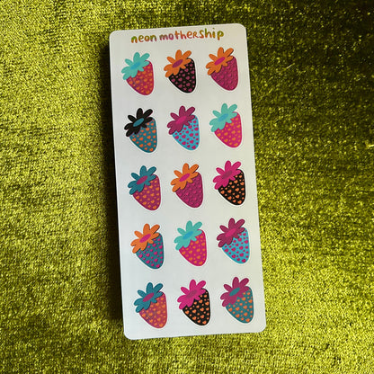 Sheet of colorful strawberry-shaped stickers on a green textured background