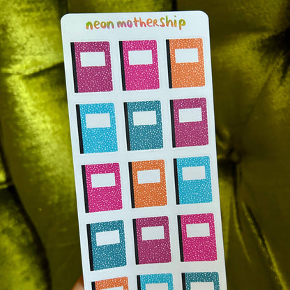 Card with colorful square notebook stickers labeled 'neon mothership' held by a hand against a green fabric background.