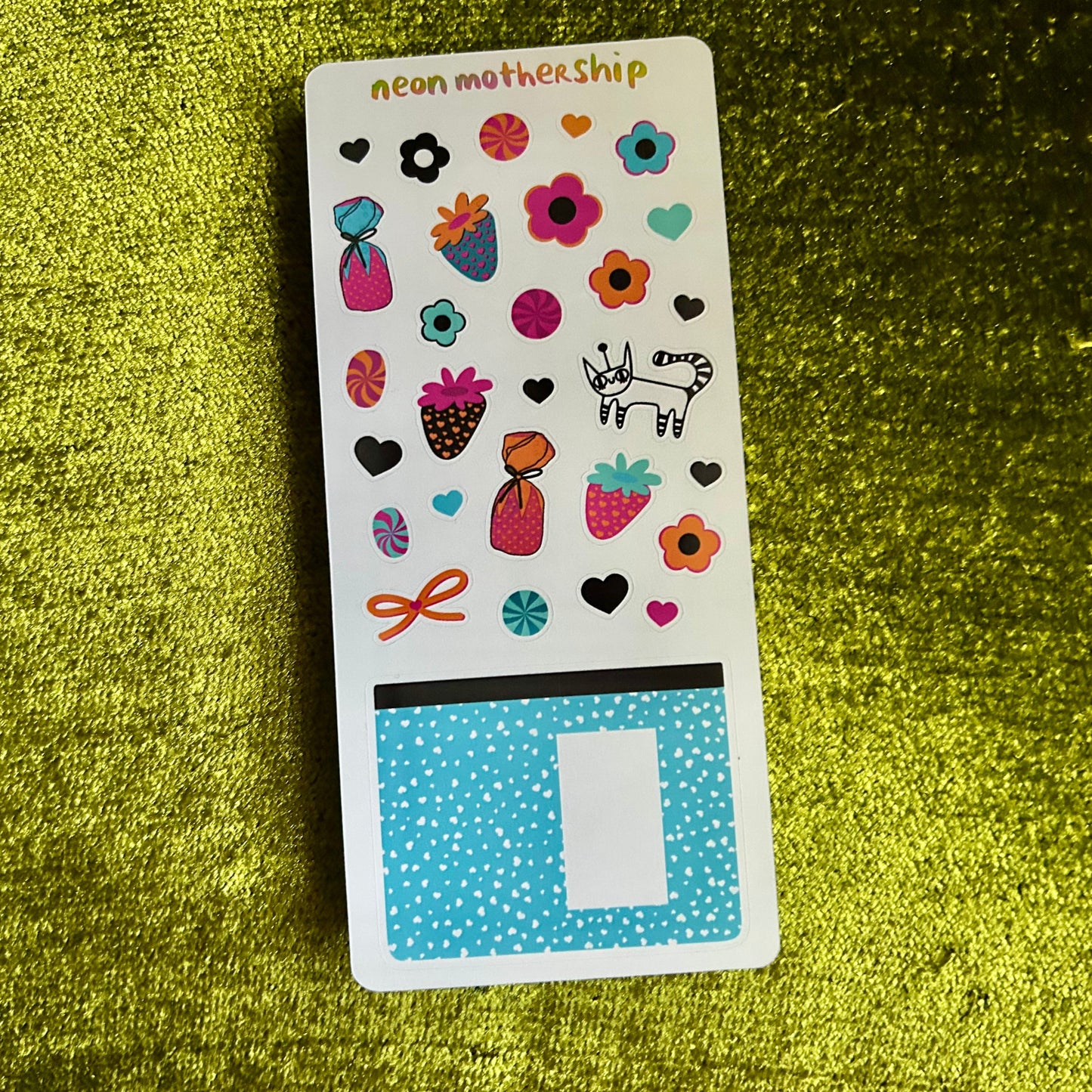 Sticker sheet with colorful designs on a green textured surface
