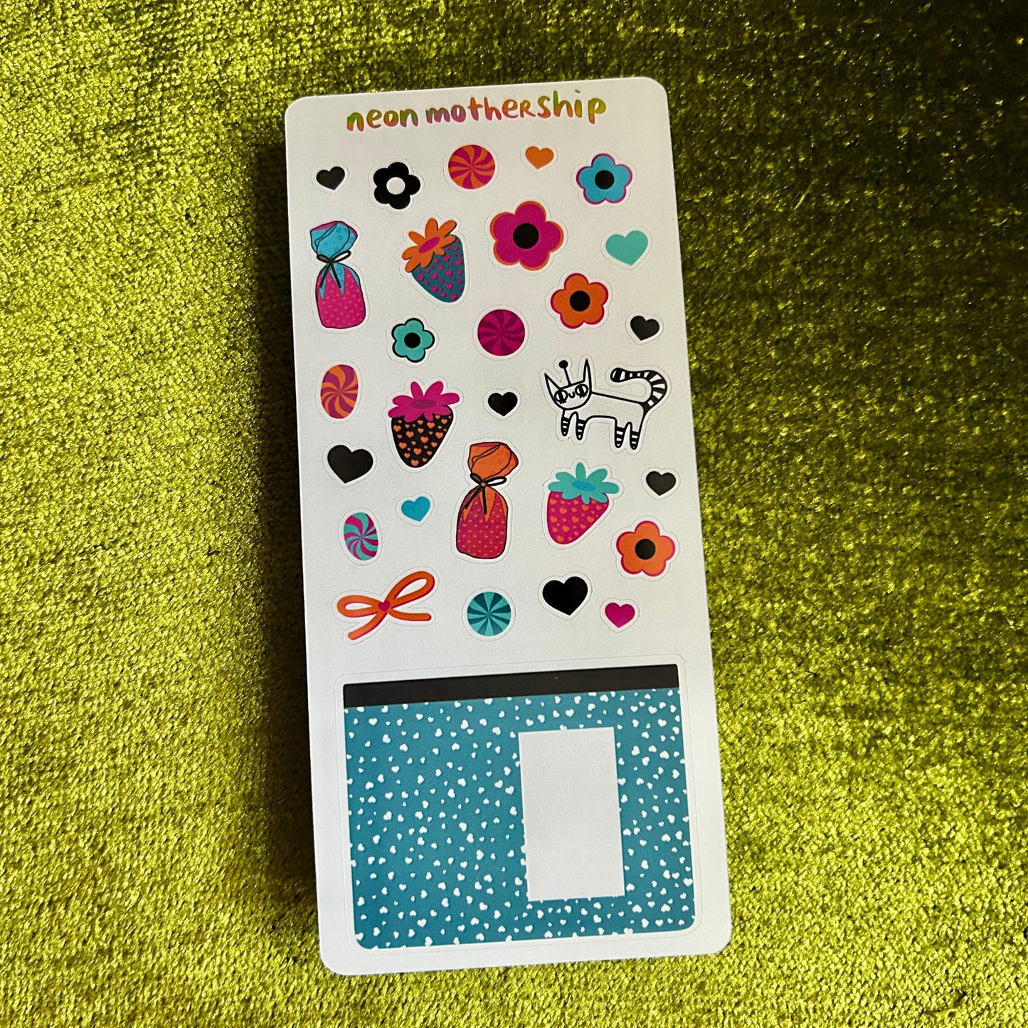 Sticker sheet with colorful designs on a green textured surface