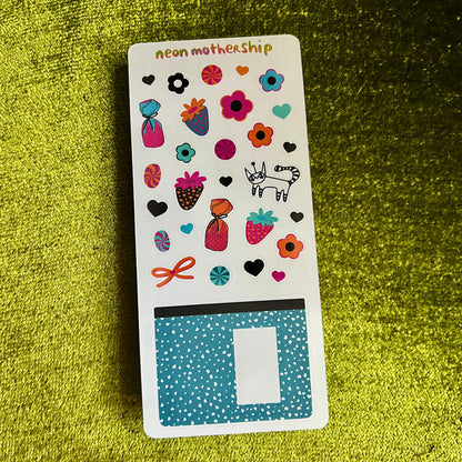 Sticker sheet with colorful designs on a green textured surface