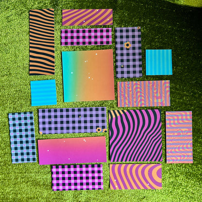 Collection of colorful patterned sticker paper sheets on a green textured surface