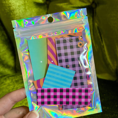 Holographic packaging with colorful stationery items against a green background