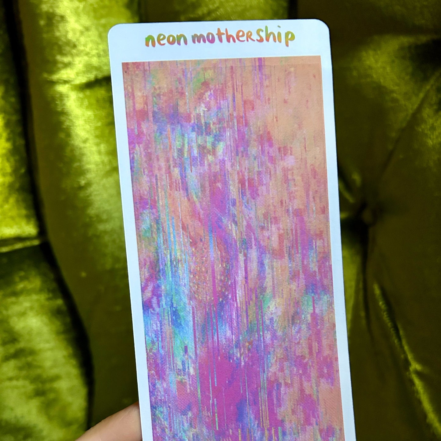 Colorful card with 'neon mothership' text held against a green velvet background