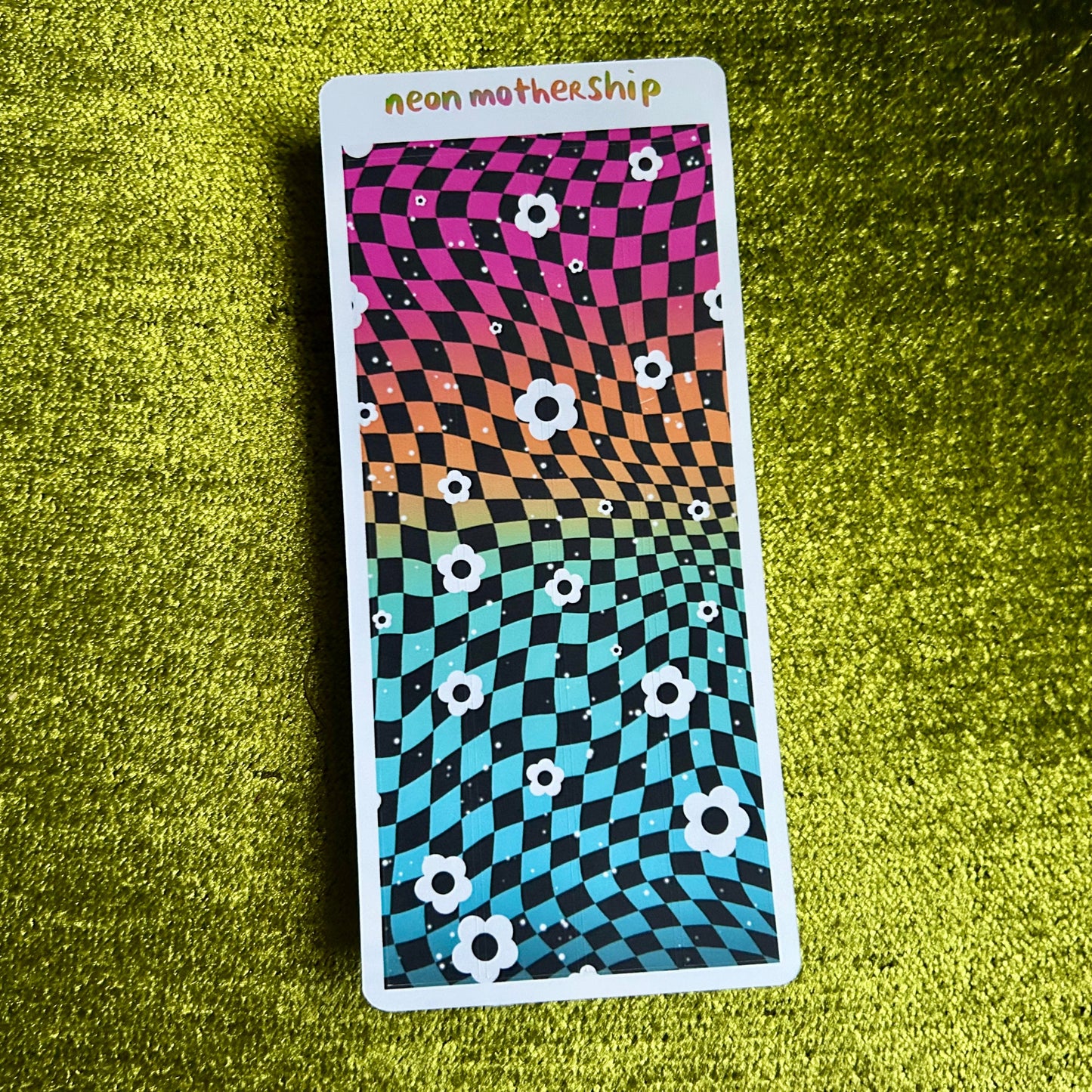 Colorful patterned card with 'neon motherShip' text on a green textured surface