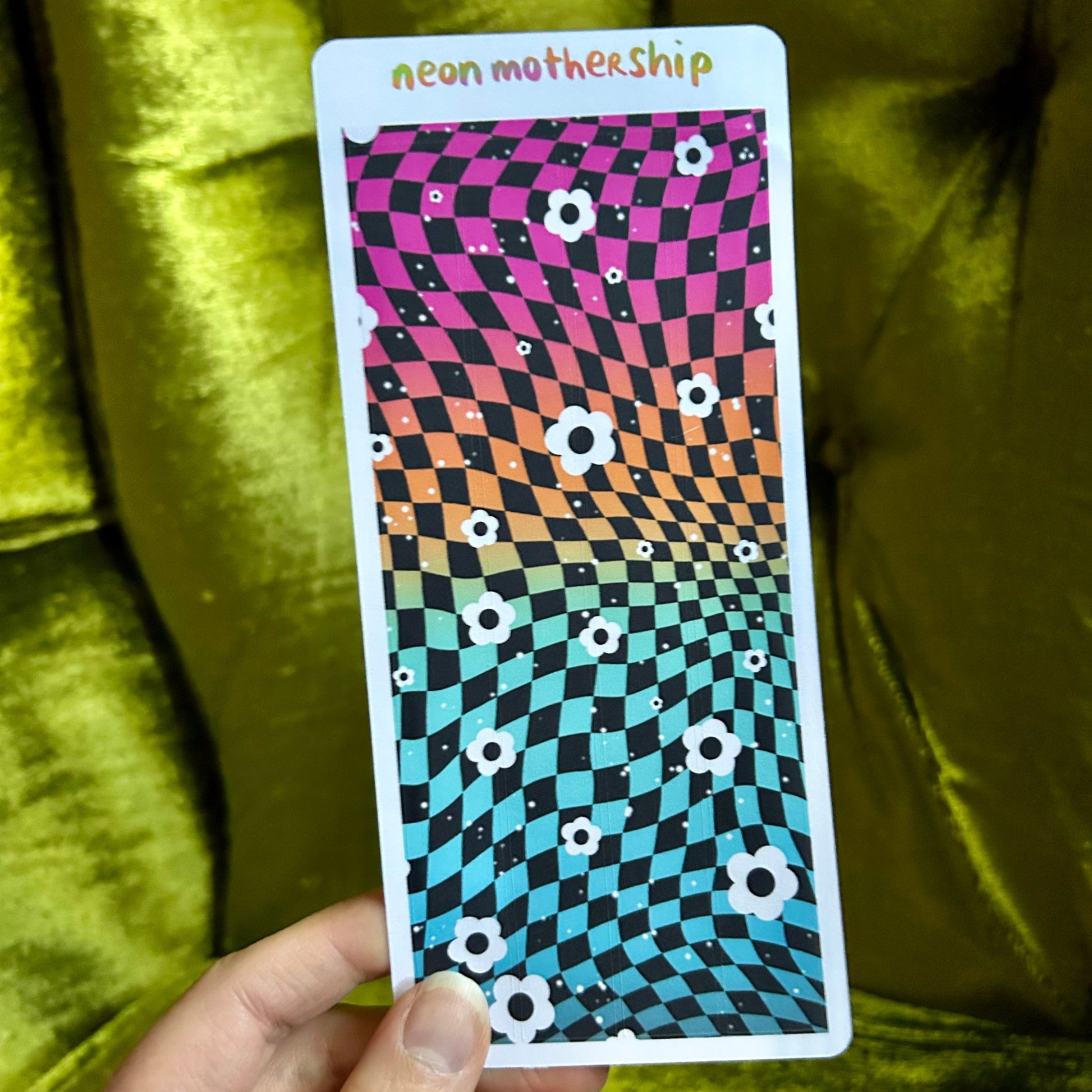 Colorful checkered sticker sheet by a hand against a green velvet background