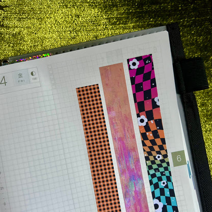 Planner with colorful washi tape strips on a textured green surface