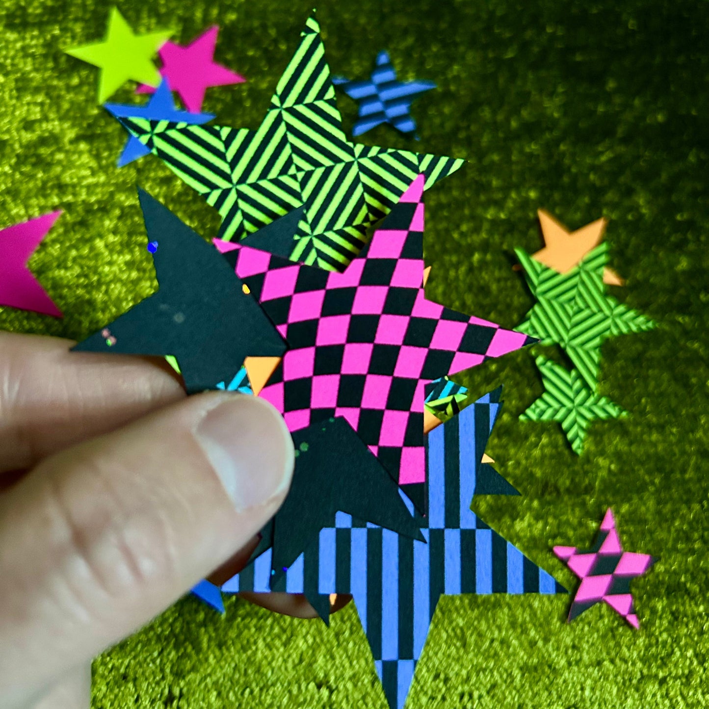 Colorful star-shaped paper cutouts on a green textured background