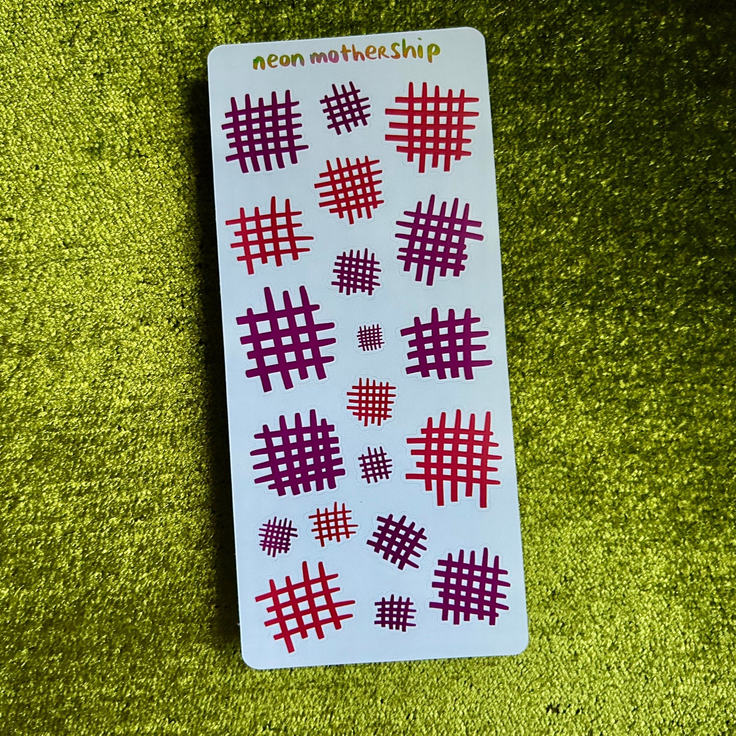 Card with red and purple patterns on a green textured surface