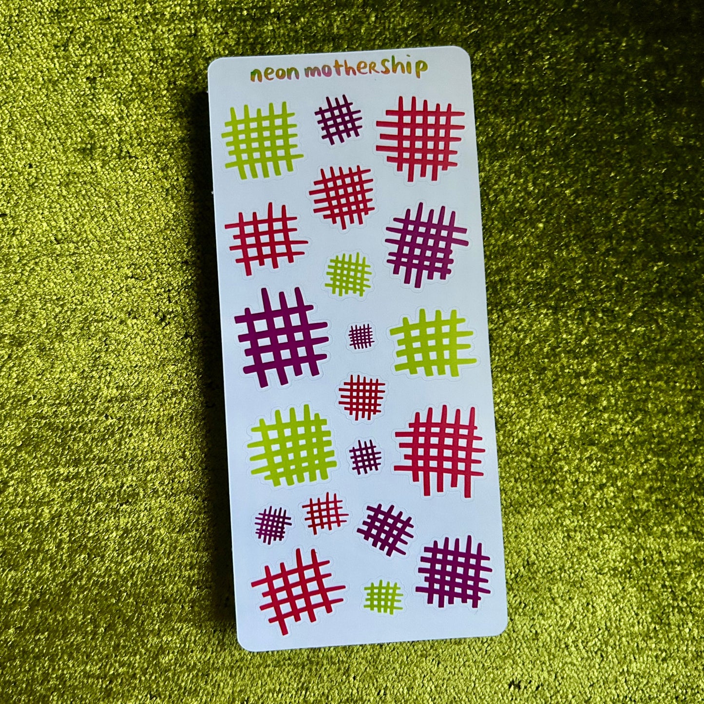 Card with red and green checkered patterns on a green textured surface