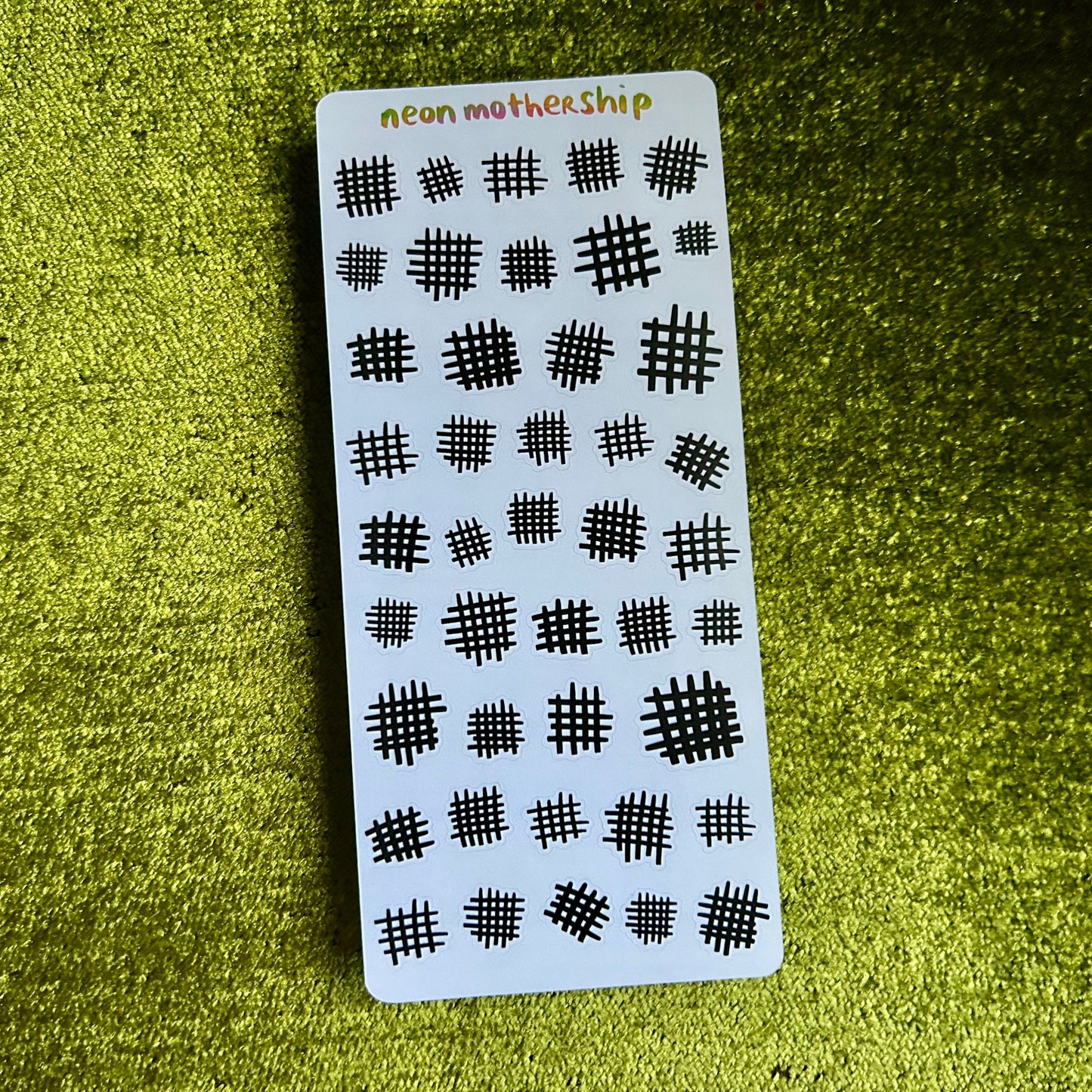 Sticker sheet with black patterns on a white card against a green textured background