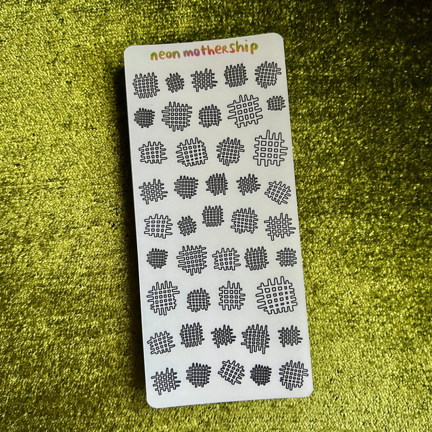 Card with black geometric patterns on a green textured surface