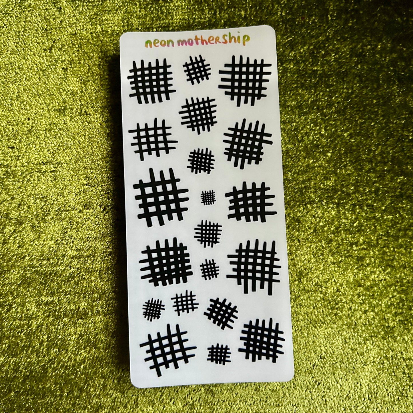 sticker sheet with grid pattern stickers on a green textured surface