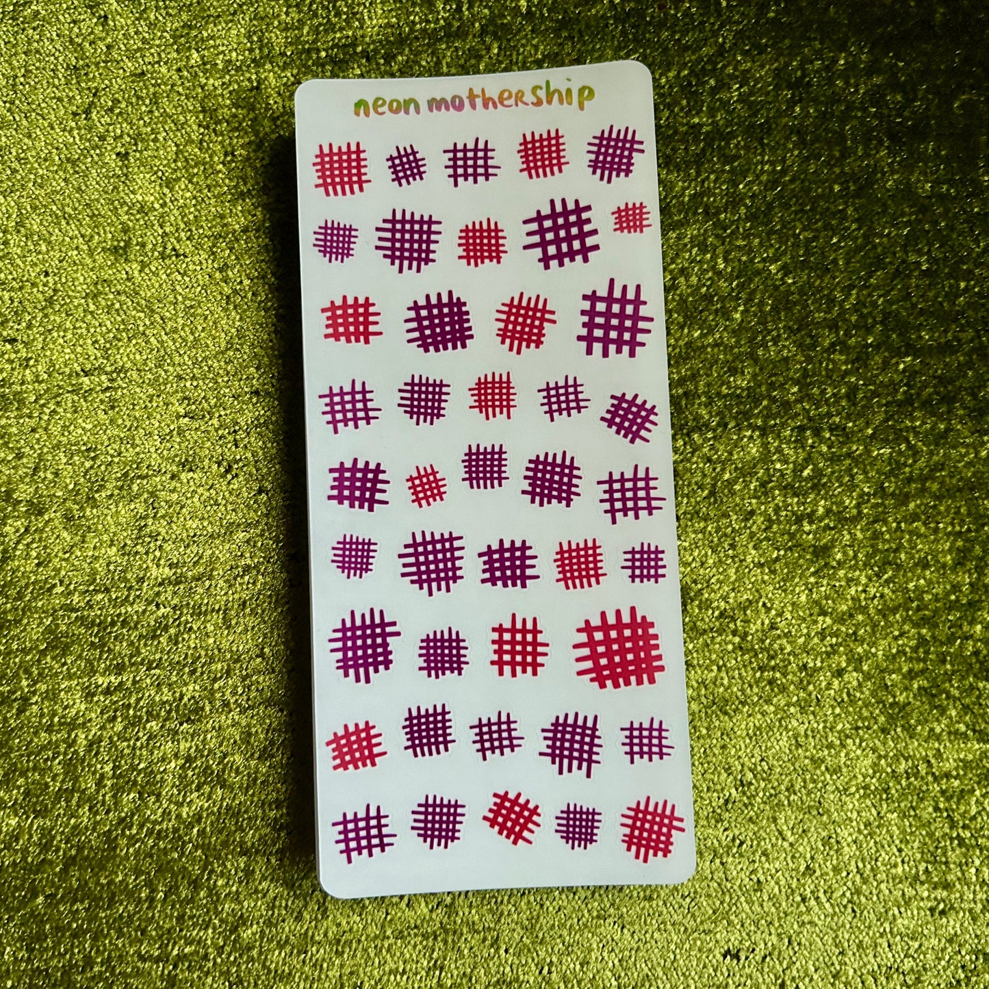 Sheet of red and white patterned stickers on a textured green surface