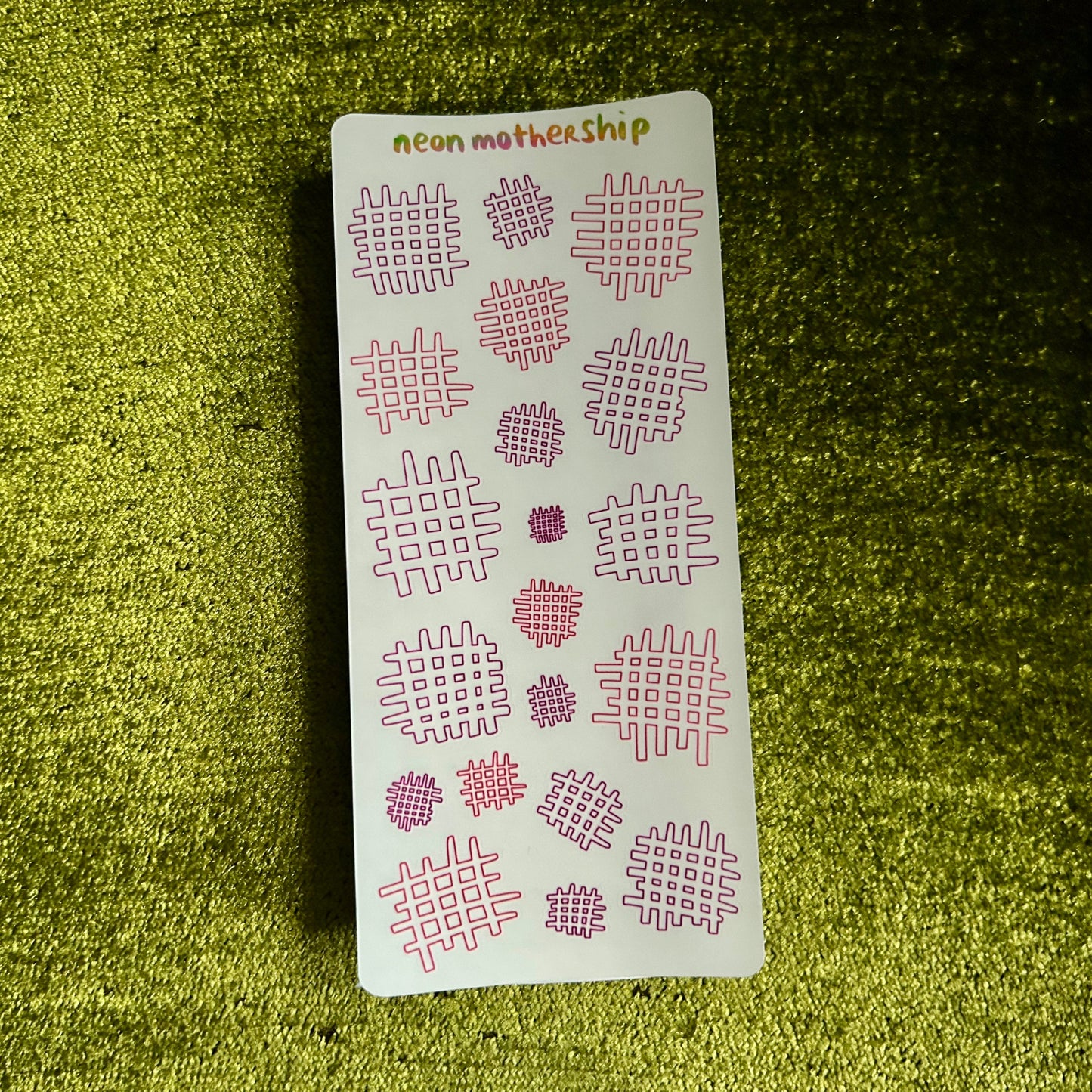Sheet of pink geometric stickers on a green textured surface