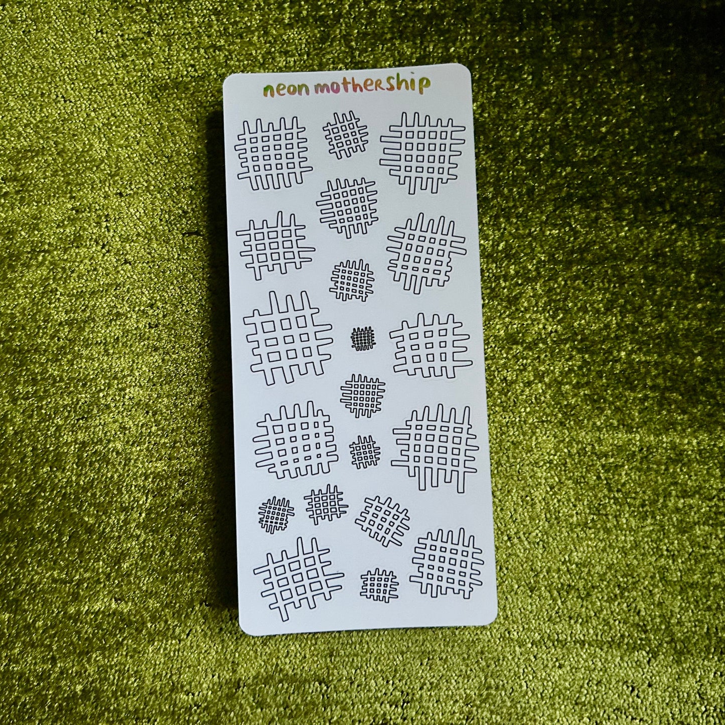 Sheet of stencils with '#' pattern on a green textured surface