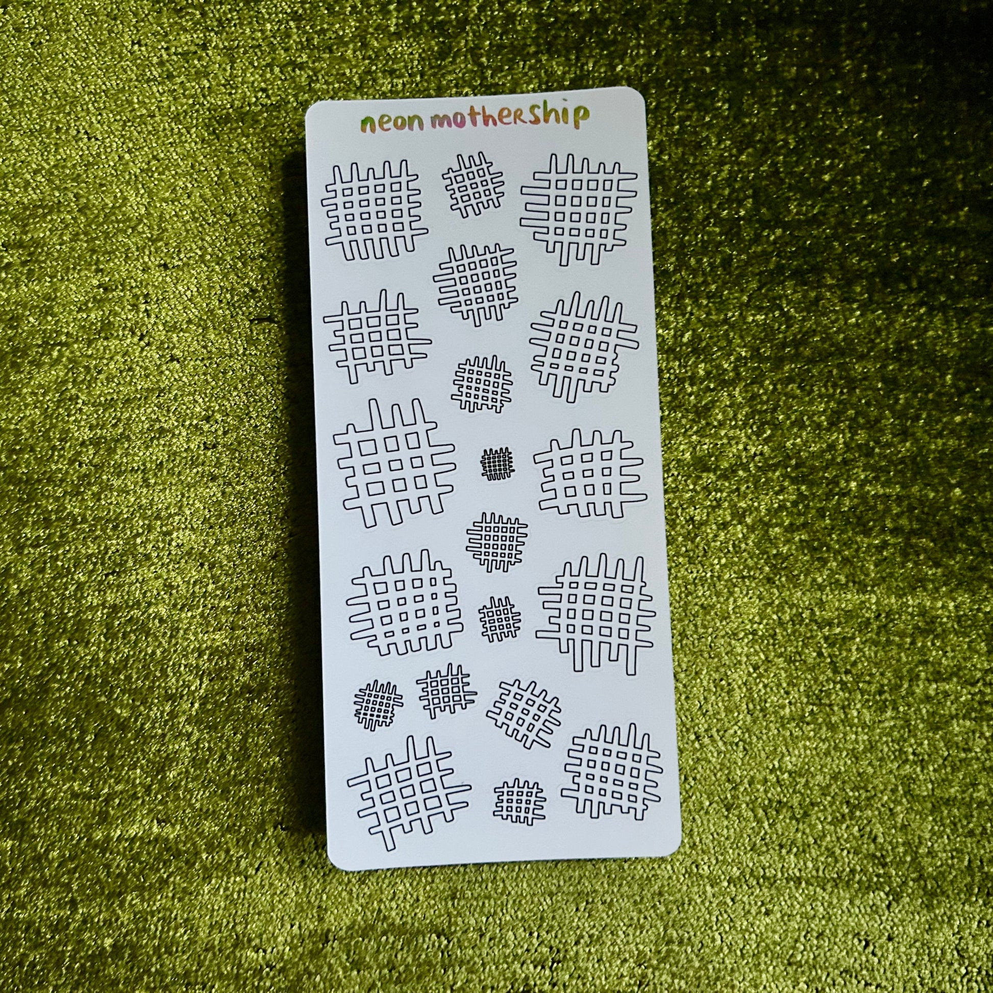 Sheet of stencils with '#' pattern on a green textured surface