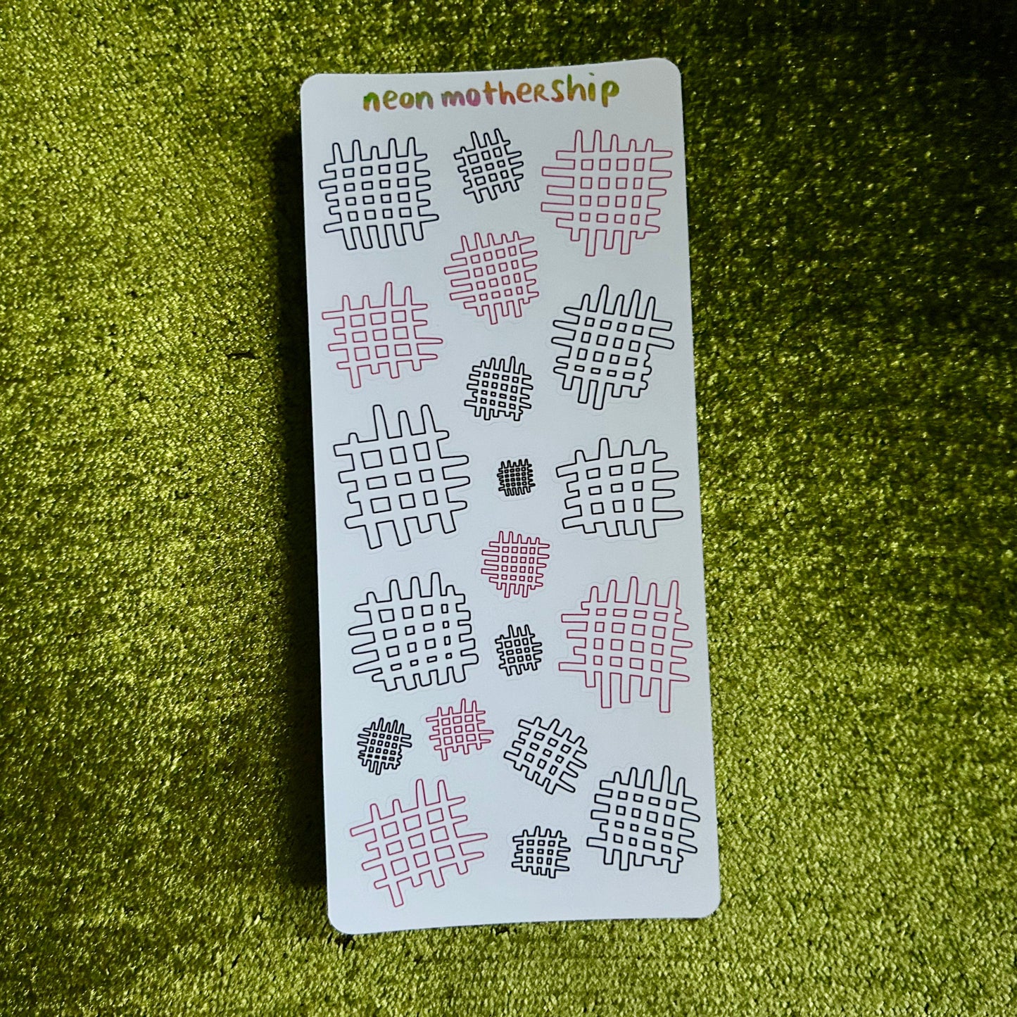 Sheet of patterned stickers with '#', 'x', and other symbols on a green textured surface.