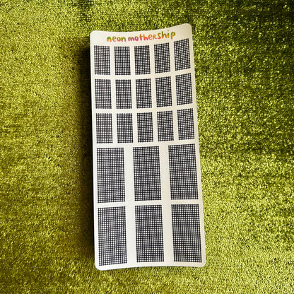 Small rectangular sticker sheet with grid pattern on a green textured surface