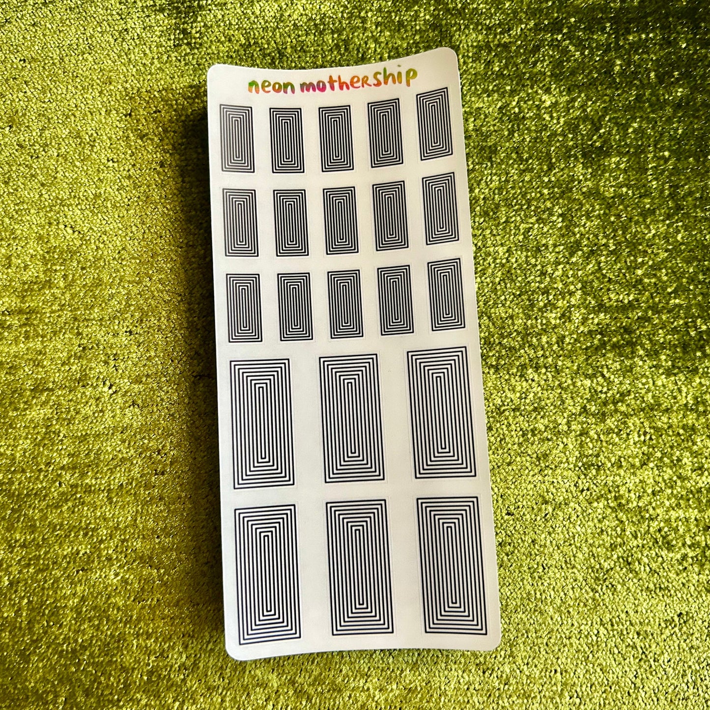 Sheet of black and white patterned stickers on a green textured surface