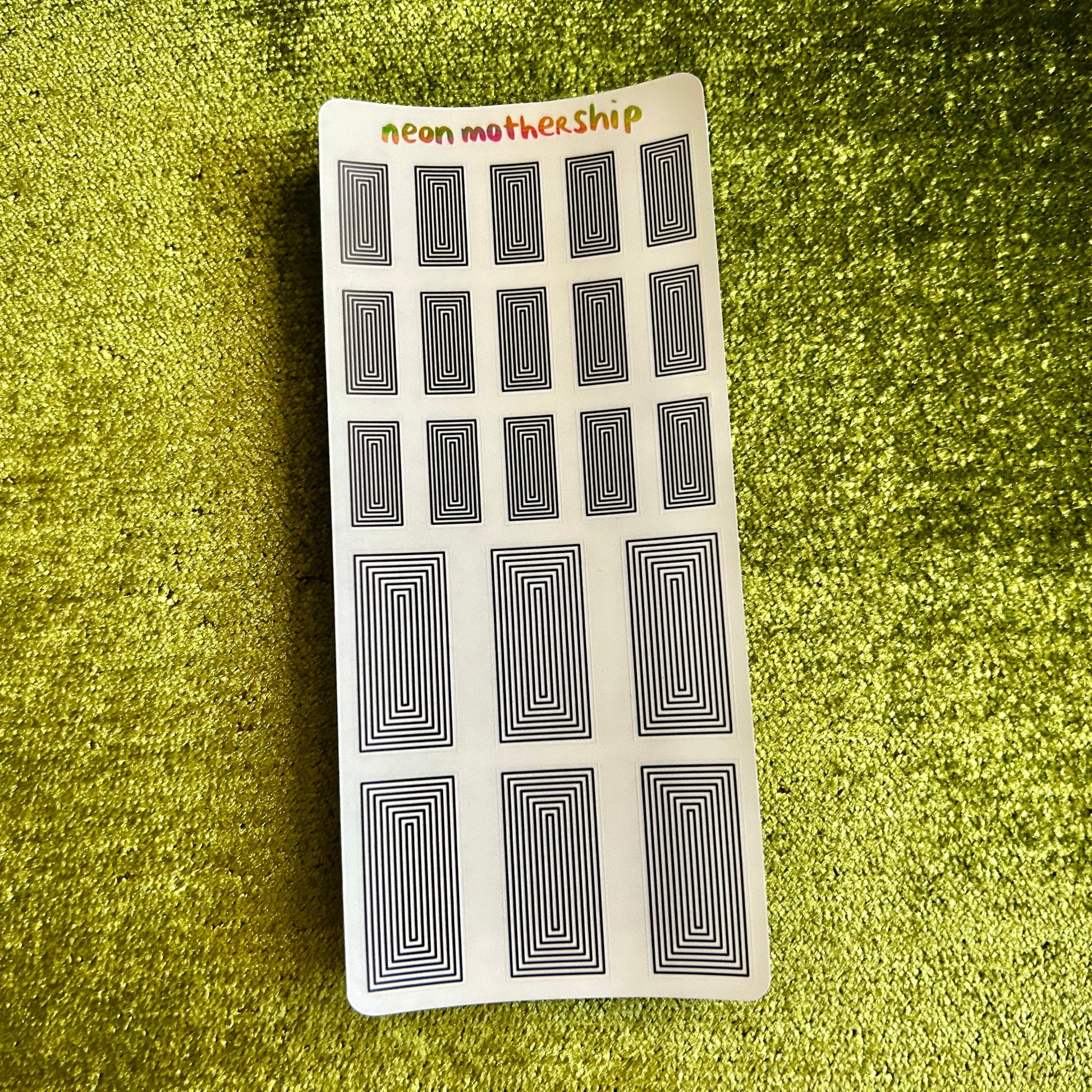Sheet of black and white patterned stickers on a green textured surface