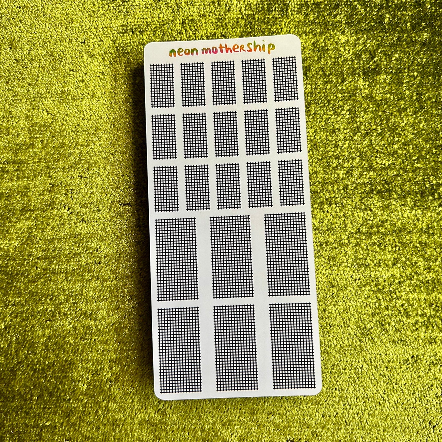 Rectangular grid sticker sheet with 'neon motherShip' branding on a green textured background