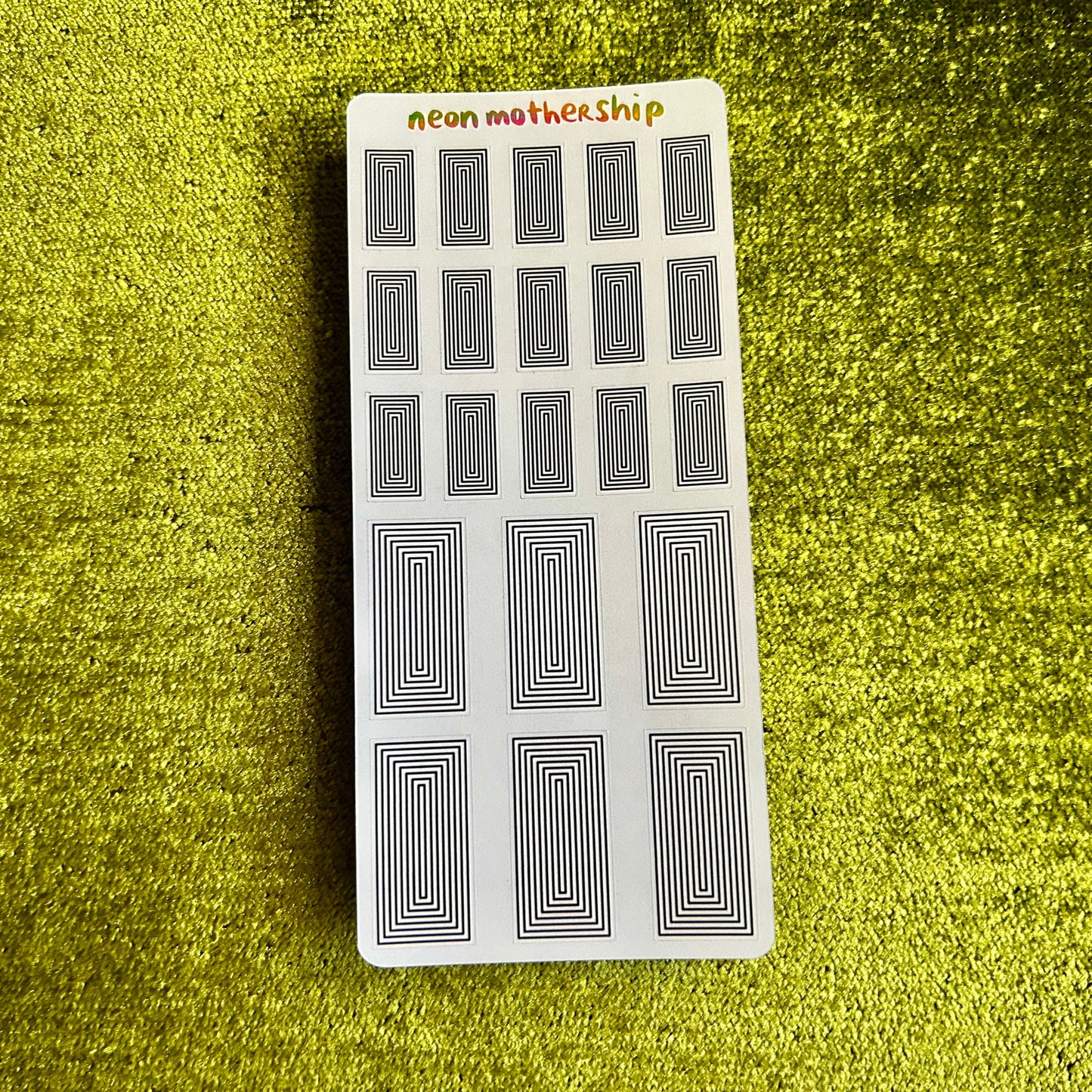 sticker sheet with black patterns on a green textured surface