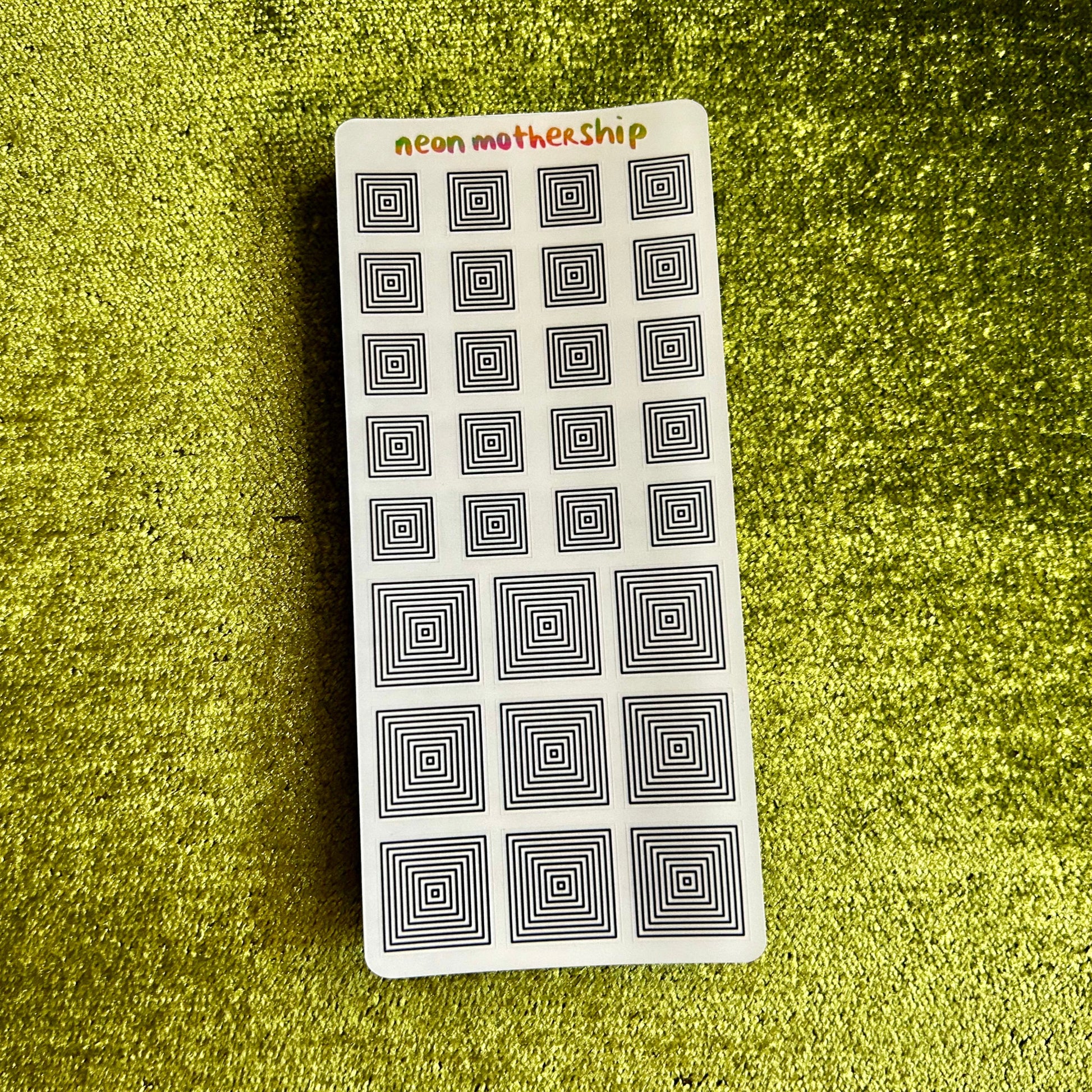 Rectangular sticker sheet with geometric patterns on a green textured surface