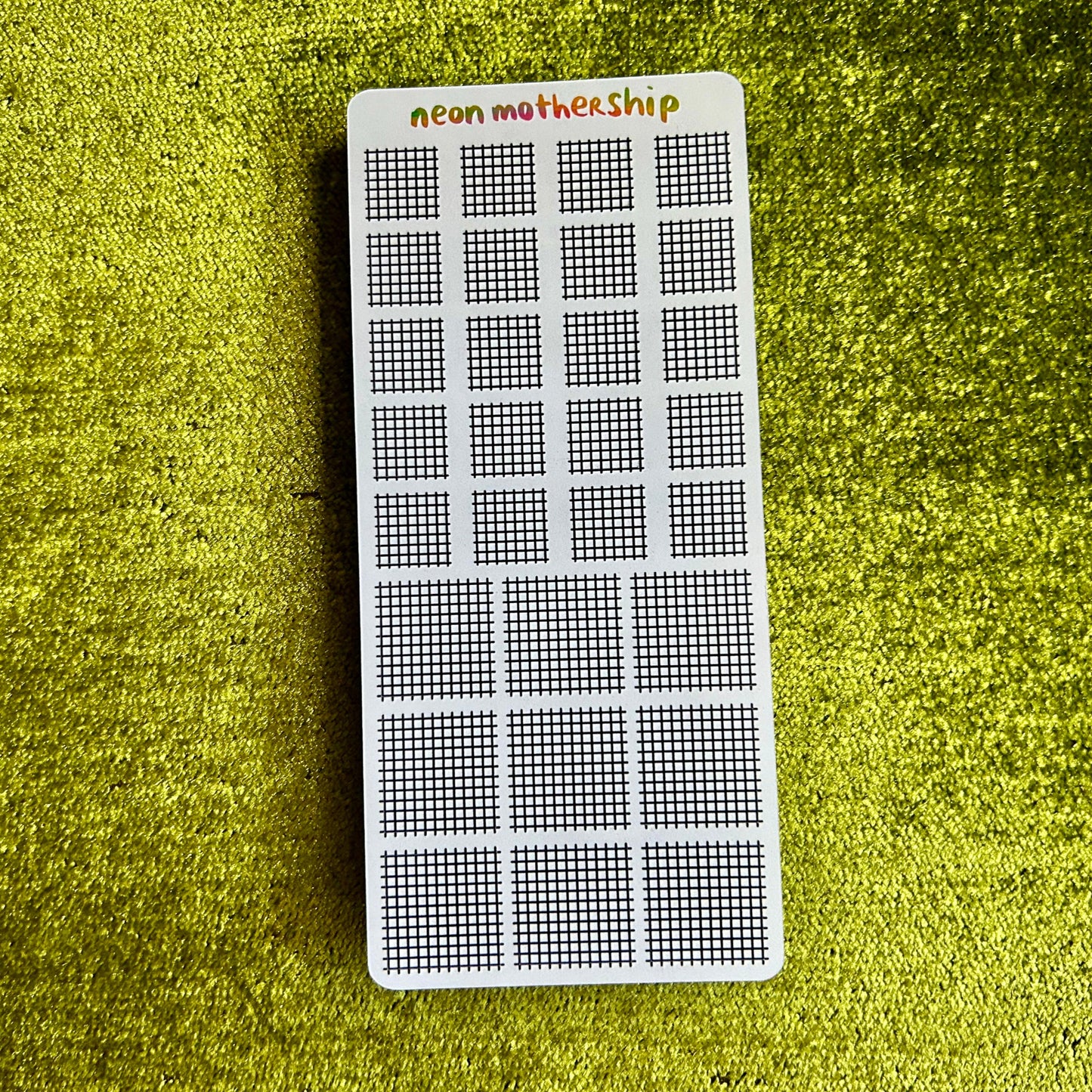 Grid-patterned sticker on a green textured surface