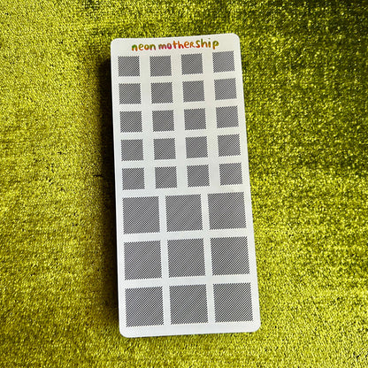 Rectangular sticker sheet with grid pattern on a green textured surface